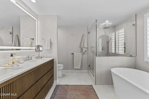 a bathroom with a tub a sink and a large mirror