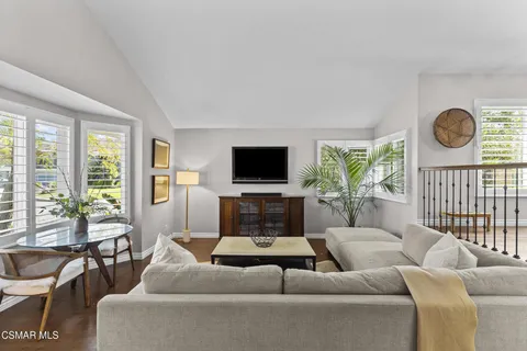 a living room with furniture a flat screen tv and a large window