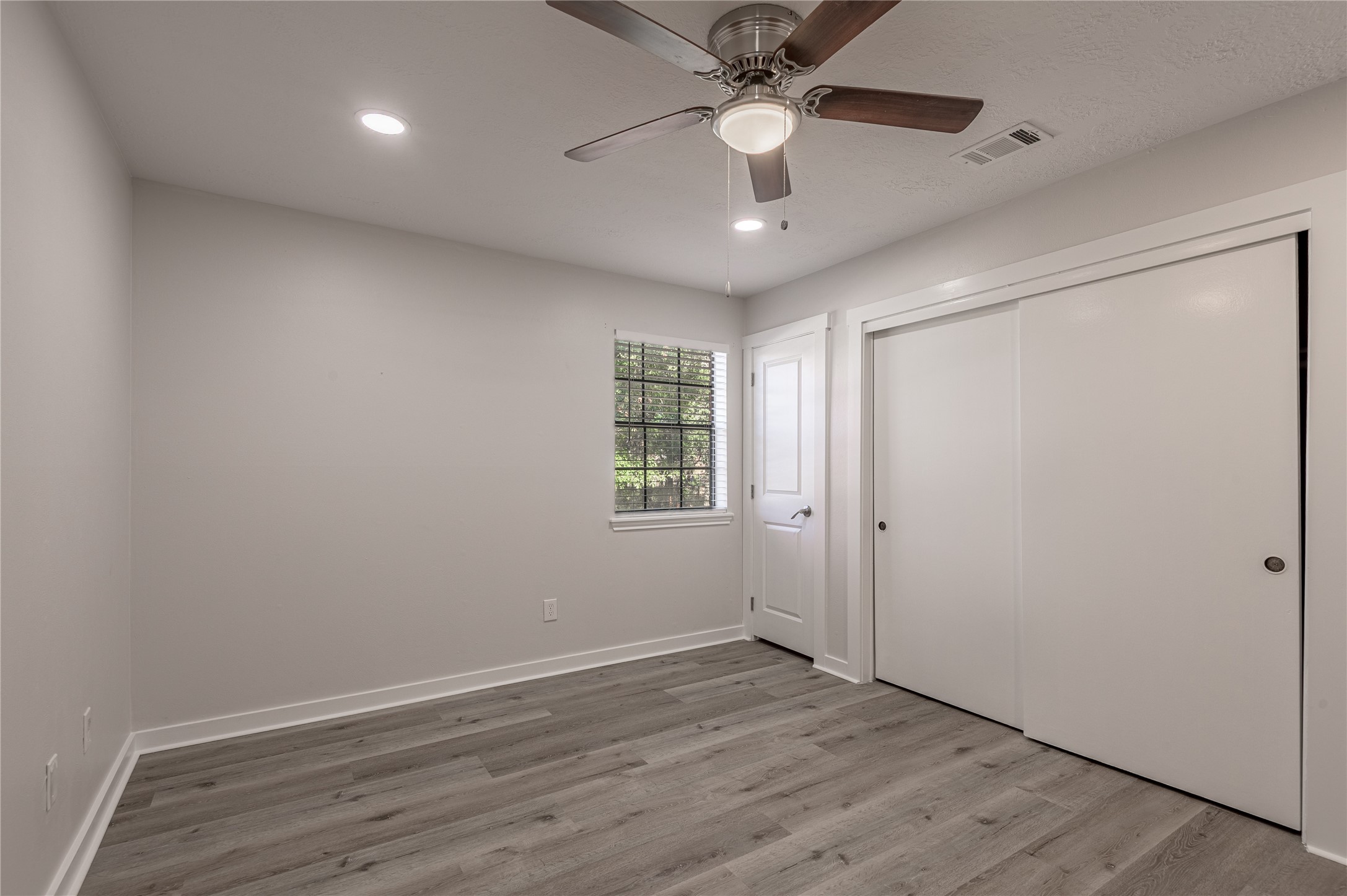 2401 Sycamore Avenue, Unit E2 Huntsville, TX 77340 - Photo 17 of 19 an empty room with wooden floor ceiling fan and windows