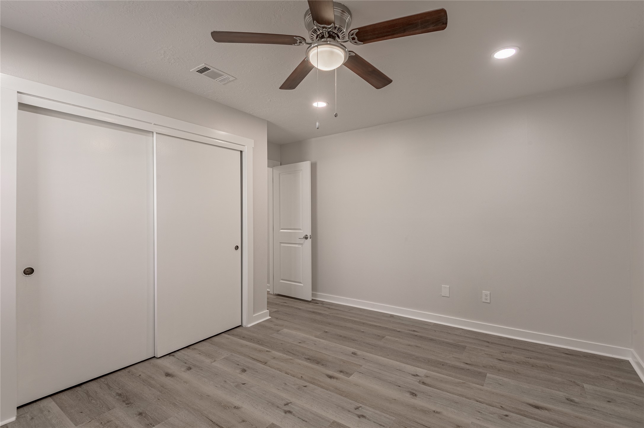 2401 Sycamore Avenue, Unit E2 Huntsville, TX 77340 - Photo 18 of 19 an empty room with wooden floor a ceiling fan and closet