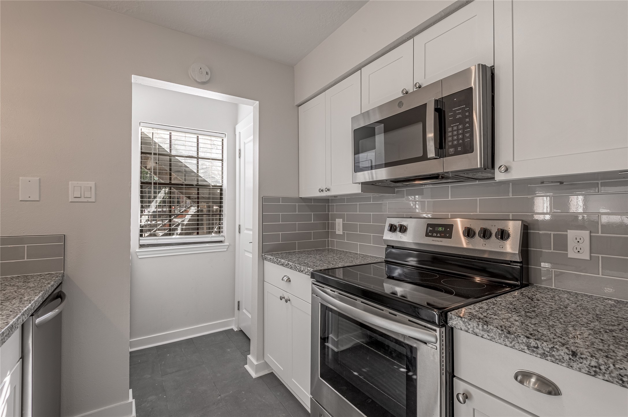 2401 Sycamore Avenue, Unit E2 Huntsville, TX 77340 - Photo 8 of 19 a kitchen with stainless steel appliances granite countertop white cabinets and a stove top oven