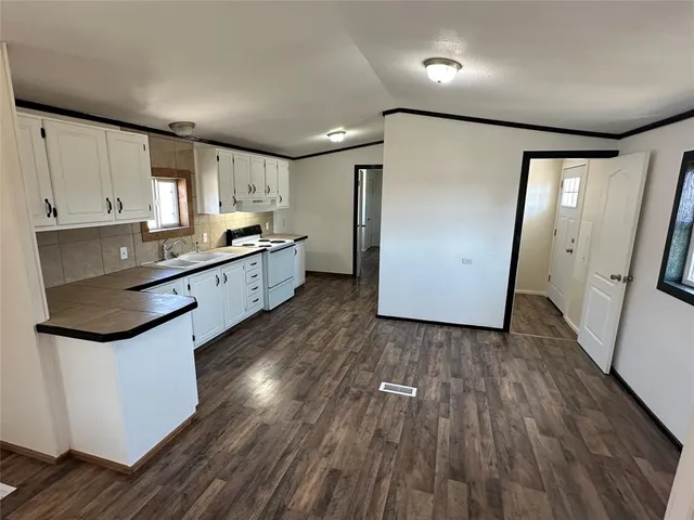 a kitchen with stainless steel appliances granite countertop wooden floors and white walls