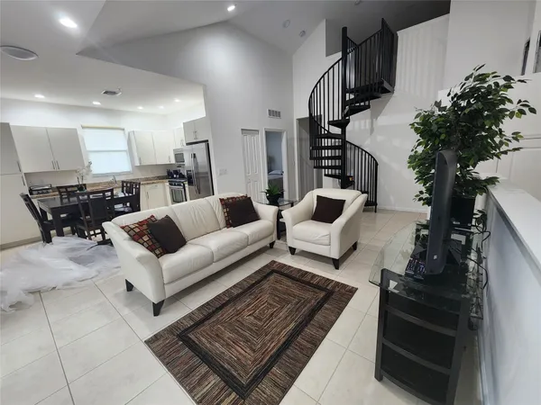 a living room with furniture kitchen view and a potted plant