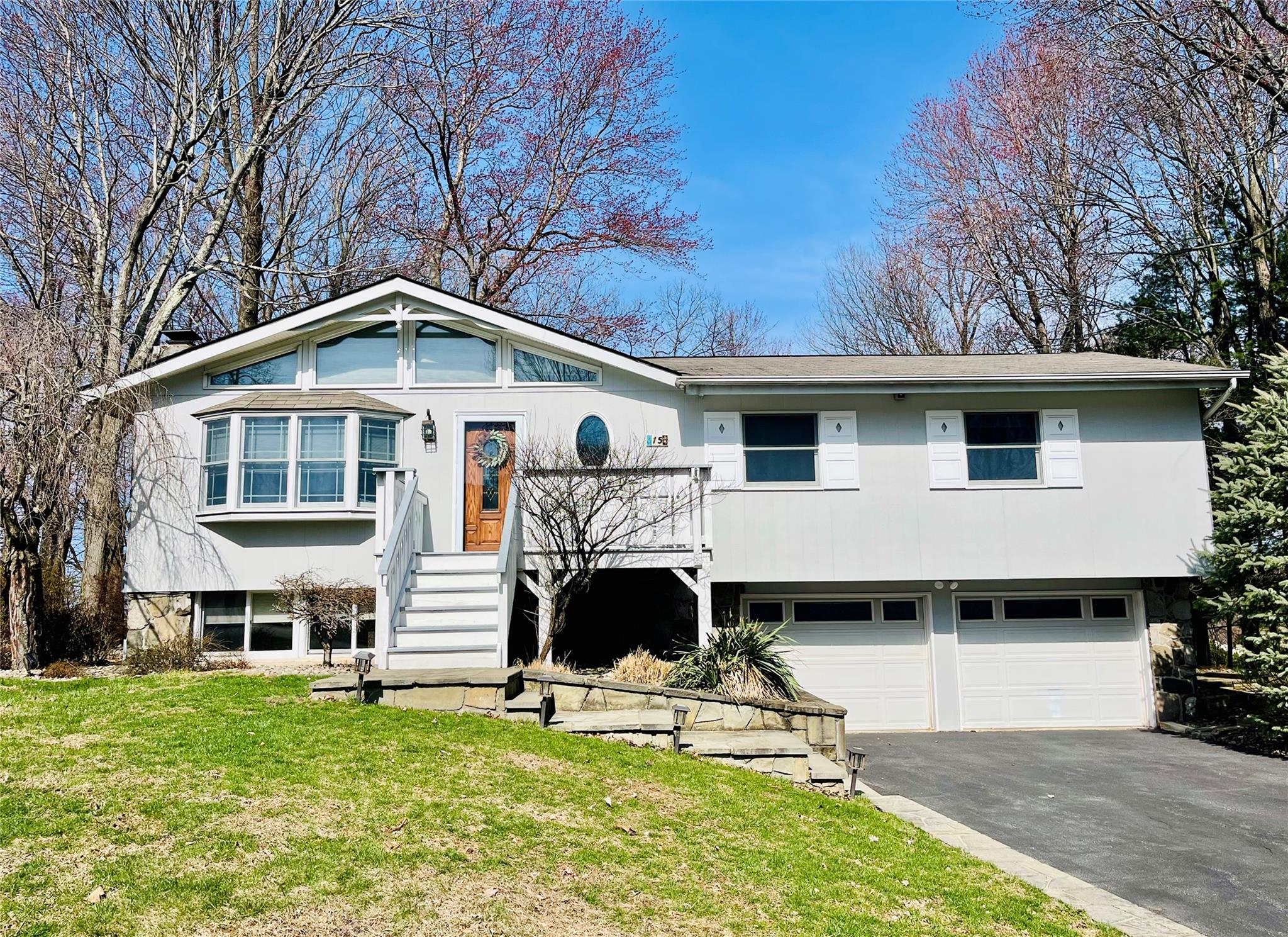 View of front of property with a front yard, driveway, and an attached garage