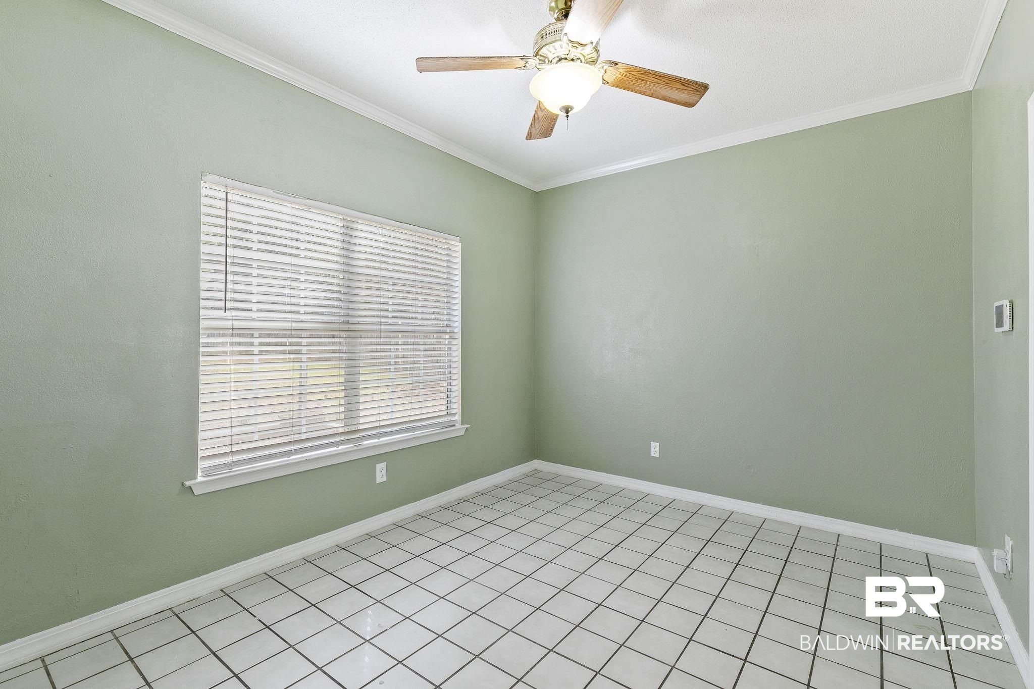 474 Ridgewood Drive Daphne, AL 36526 - Photo 18 of 57 Empty room with crown molding, light tile patterned flooring, and ceiling fan