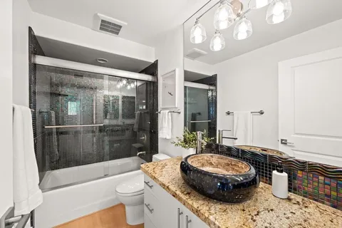 a bathroom with a granite countertop sink a toilet a mirror and shower