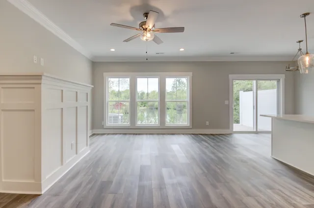 a view of an empty room with a window and wooden floor