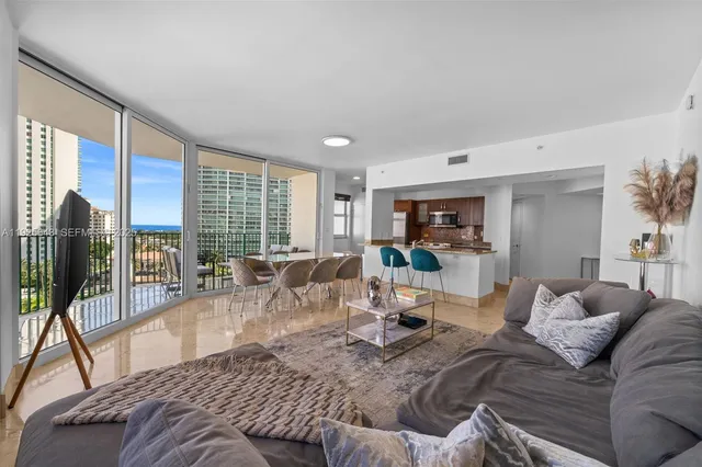 a living room with furniture large windows and wooden floor
