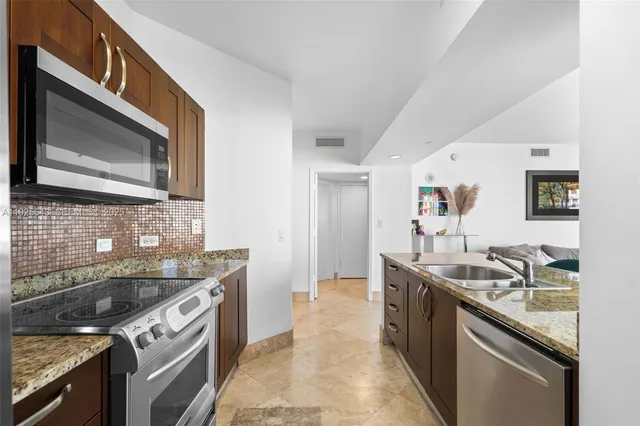 a kitchen with granite countertop stainless steel appliances sink stove microwave and cabinets