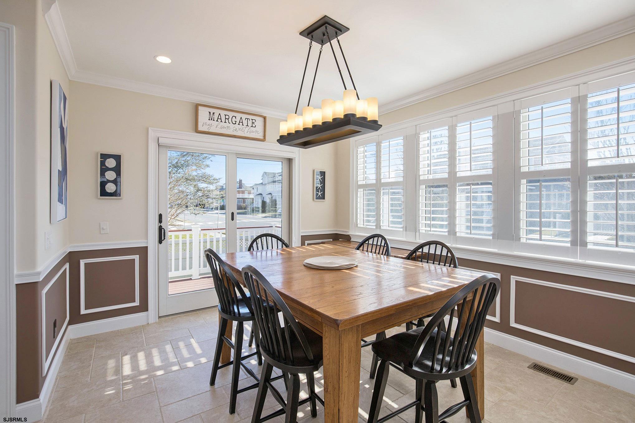 7611 Ventnor Avenue, Unit JUNE 2026 Margate City, NJ 08402 - Photo 12 of 49 a dining room with furniture a chandelier and a rug