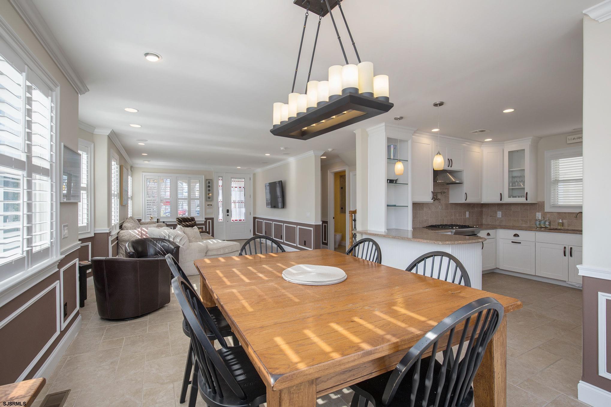 7611 Ventnor Avenue, Unit JUNE 2026 Margate City, NJ 08402 - Photo 13 of 49 a dining room filled chandelier and kitchen view