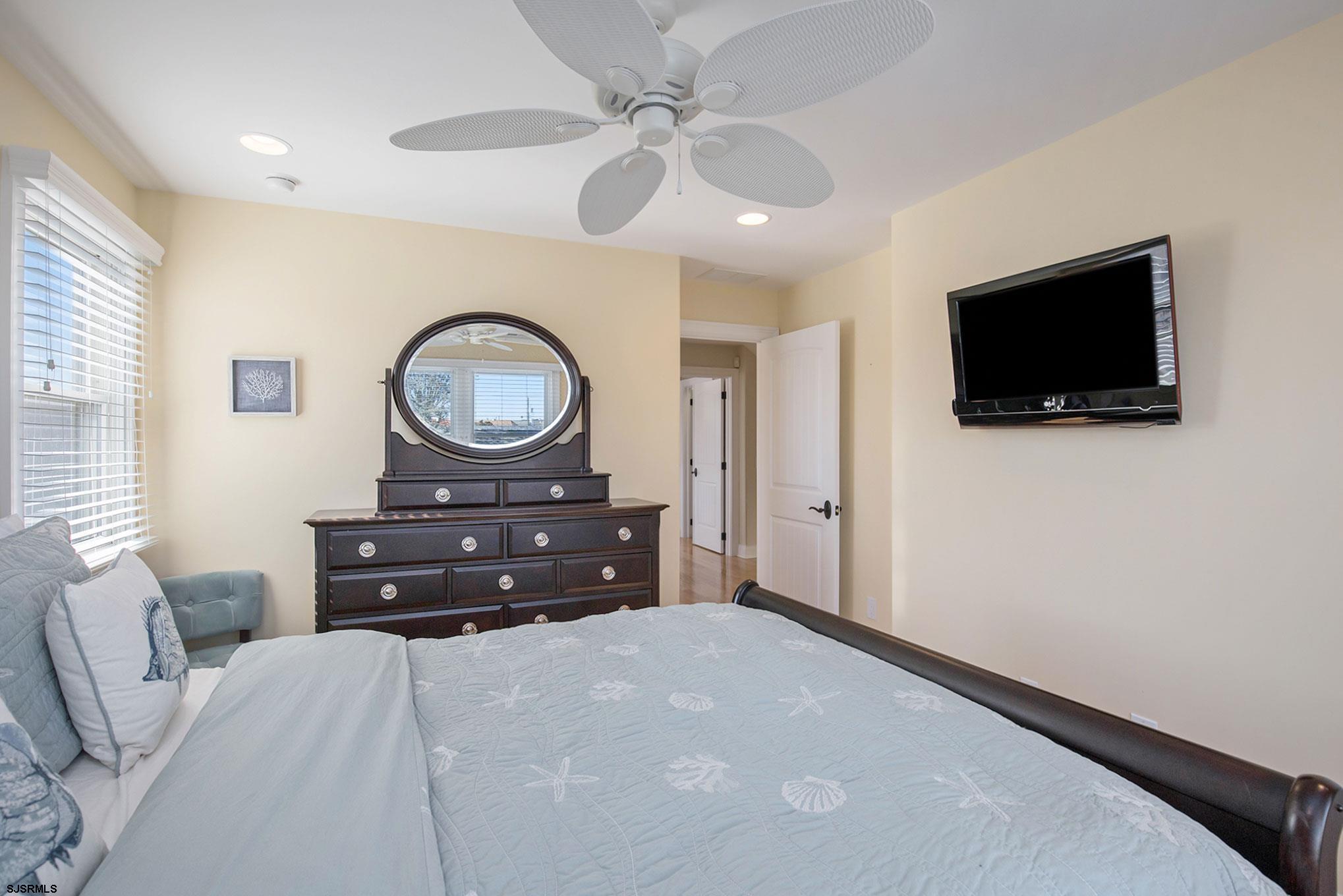 7611 Ventnor Avenue, Unit JUNE 2026 Margate City, NJ 08402 - Photo 26 of 49 a bedroom with a bed a mirror and a flat screen tv