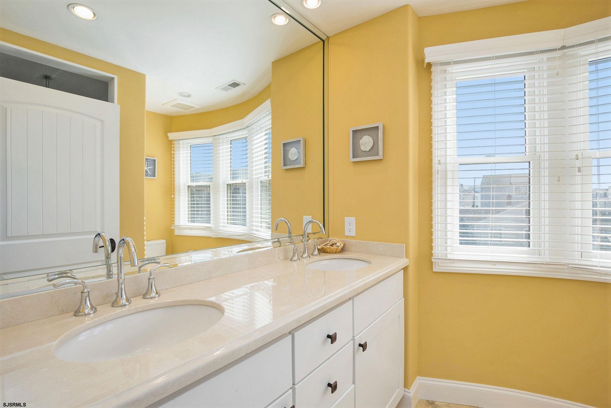 7611 Ventnor Avenue, Unit JUNE 2026 Margate City, NJ 08402 - Photo 27 of 49 a bathroom with a granite countertop sink and a large mirror