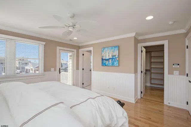 a bedroom with a bed and a large window with wooden floor