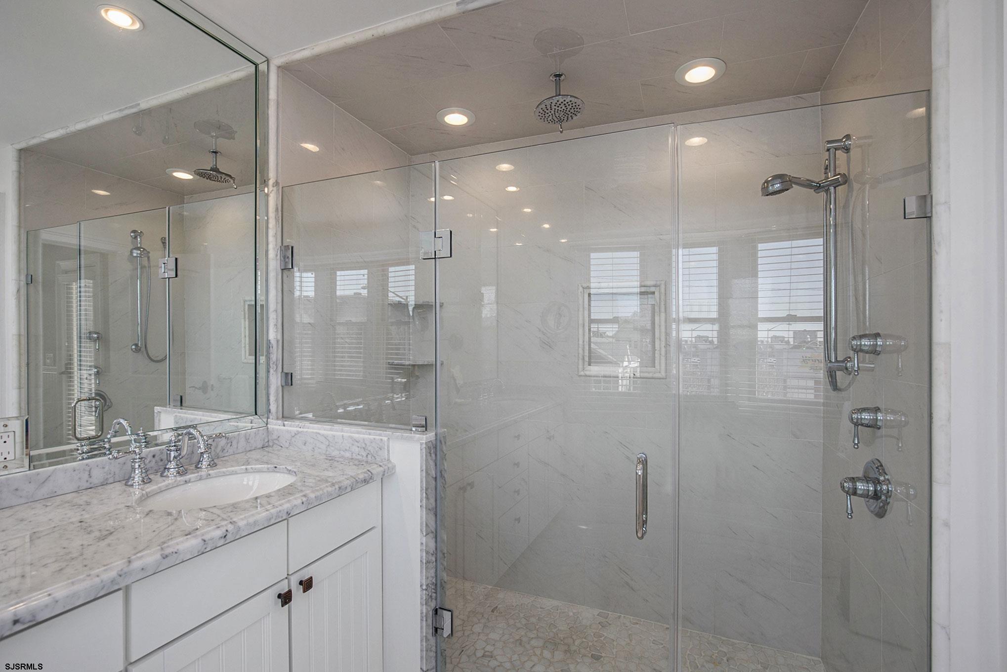 7611 Ventnor Avenue, Unit JUNE 2026 Margate City, NJ 08402 - Photo 34 of 49 a bathroom with a granite countertop sink a shower and a mirror