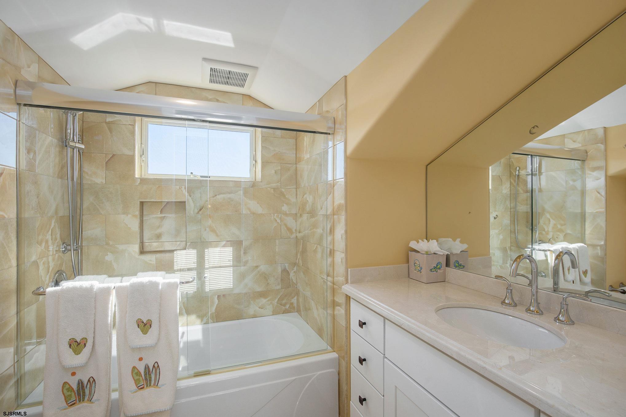 7611 Ventnor Avenue, Unit JUNE 2026 Margate City, NJ 08402 - Photo 44 of 49 a bathroom with a granite countertop sink a toilet and shower