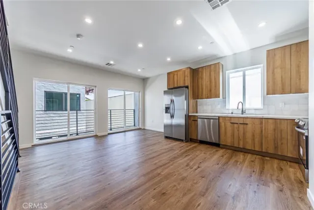 a view of kitchen with stainless steel appliances wooden floor large window and wooden floor