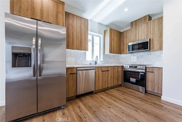 a kitchen with stainless steel appliances granite countertop a refrigerator a sink and a stove