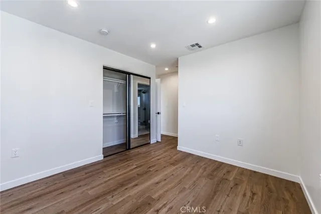 a view of an empty room with wooden floor and closet