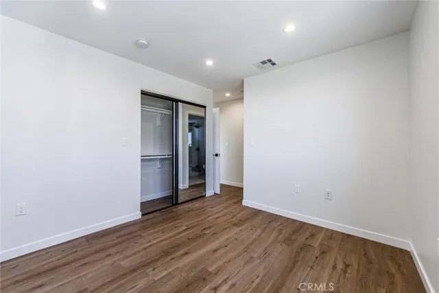 a view of an empty room with wooden floor and closet