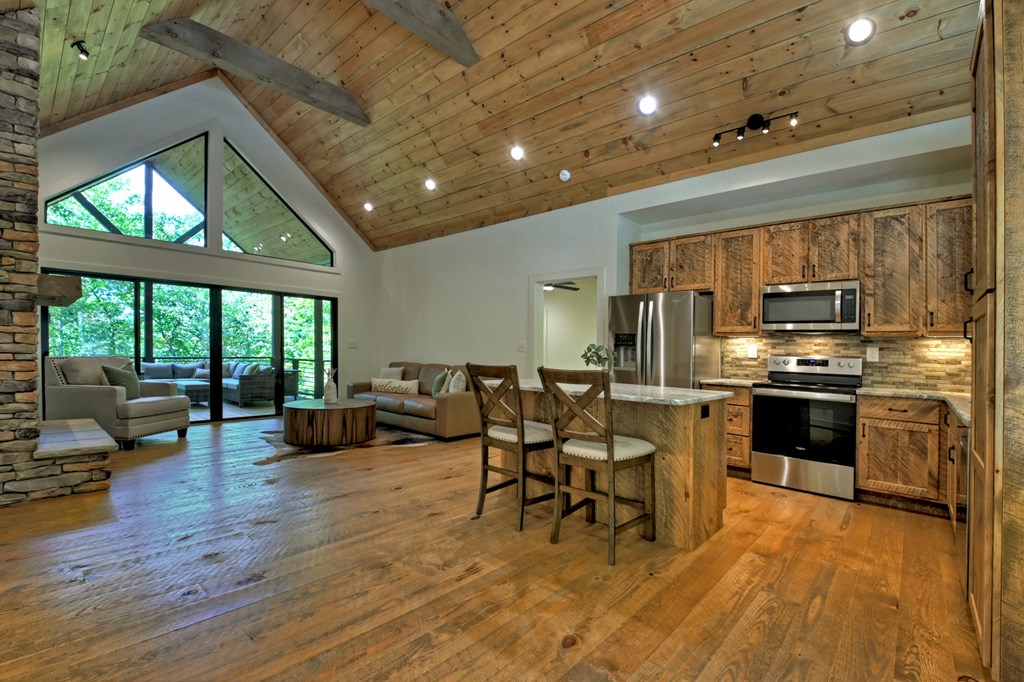 187 Chickadee Road Morganton, GA 30560 - Photo 74 of 94 a kitchen with stainless steel appliances kitchen island granite countertop a stove a refrigerator a couch and a dining table with wooden floor