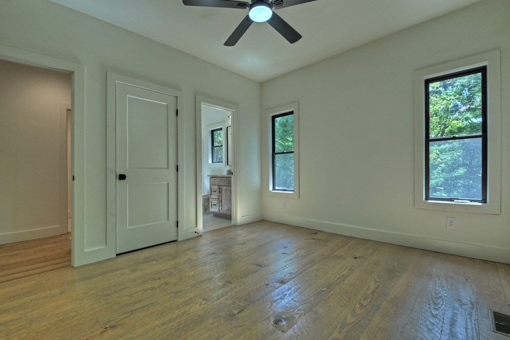 187 Chickadee Road Morganton, GA 30560 - Photo 76 of 94 an empty room with wooden floor chandelier fan and windows