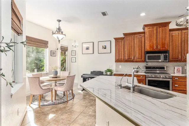 a kitchen with stainless steel appliances granite countertop a stove top oven a sink a dining table and chairs with wooden floor