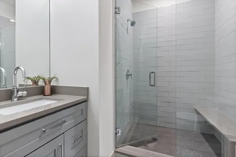 a bathroom with a granite countertop sink a mirror and shower