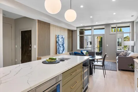 a kitchen with stainless steel appliances kitchen island granite countertop a stove a refrigerator a dining table and chairs with wooden floor