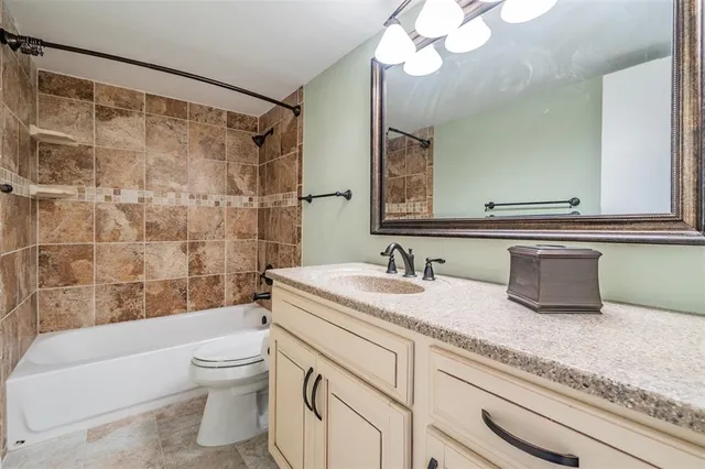a bathroom with a granite countertop sink a toilet a mirror and bathtub