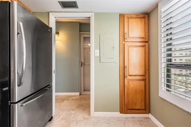 a view of hallway with a refrigerator and cabinet
