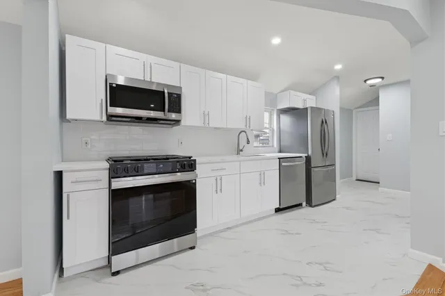 a kitchen with stainless steel appliances white cabinets white stove a microwave and a sink