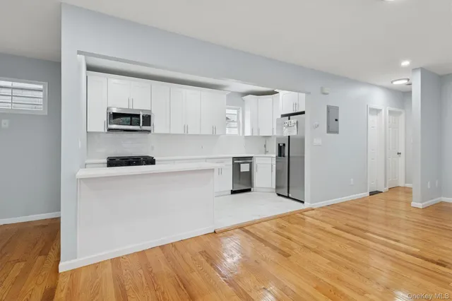 a kitchen with stainless steel appliances kitchen island granite countertop a refrigerator sink and white cabinets