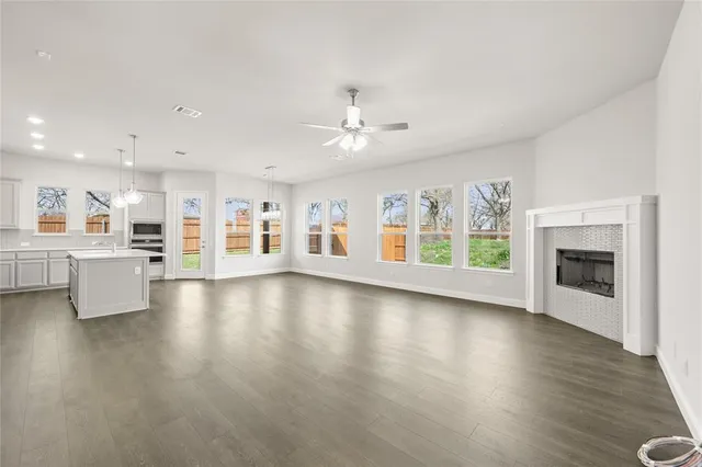 a view of an empty room with a kitchen and a fireplace