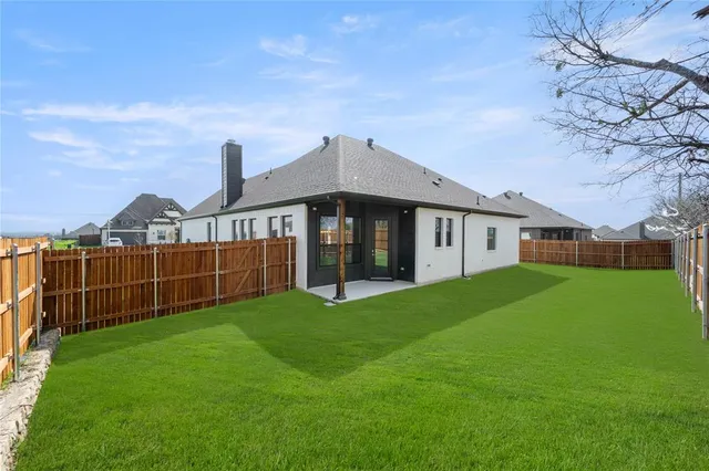 a view of a house next to a big yard and large trees