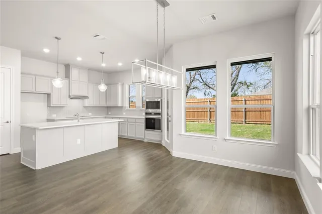 a open kitchen with white cabinets and wooden floor