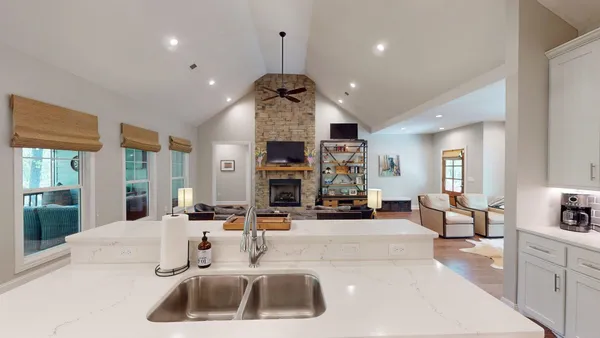 a large room with stainless steel appliances lots of white furniture a window and a couch