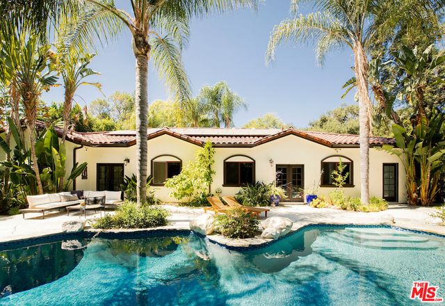 a front view of a house with swimming pool and furniture