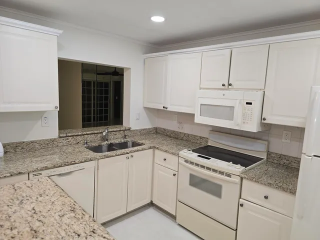 a kitchen with granite countertop white cabinets and white appliances