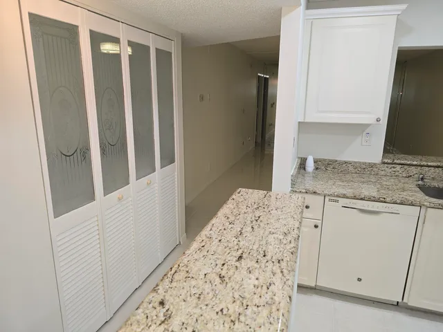 a kitchen with granite countertop white cabinets and white appliances