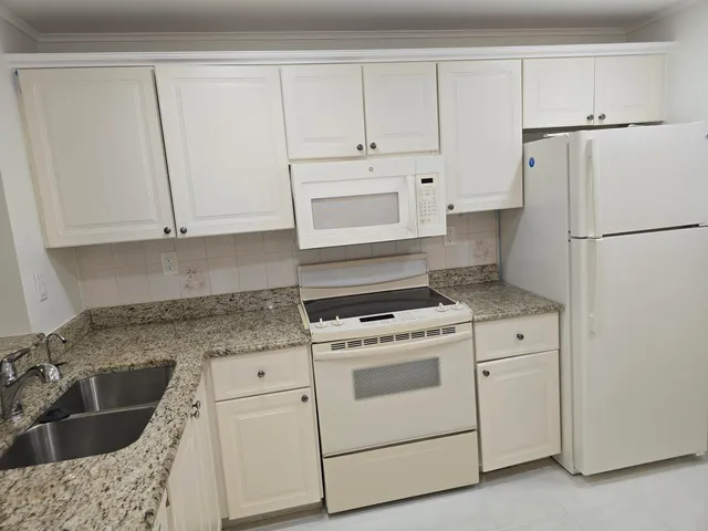 a kitchen with granite countertop white cabinets and white appliances