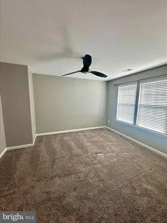 an empty room with windows and ceiling fan