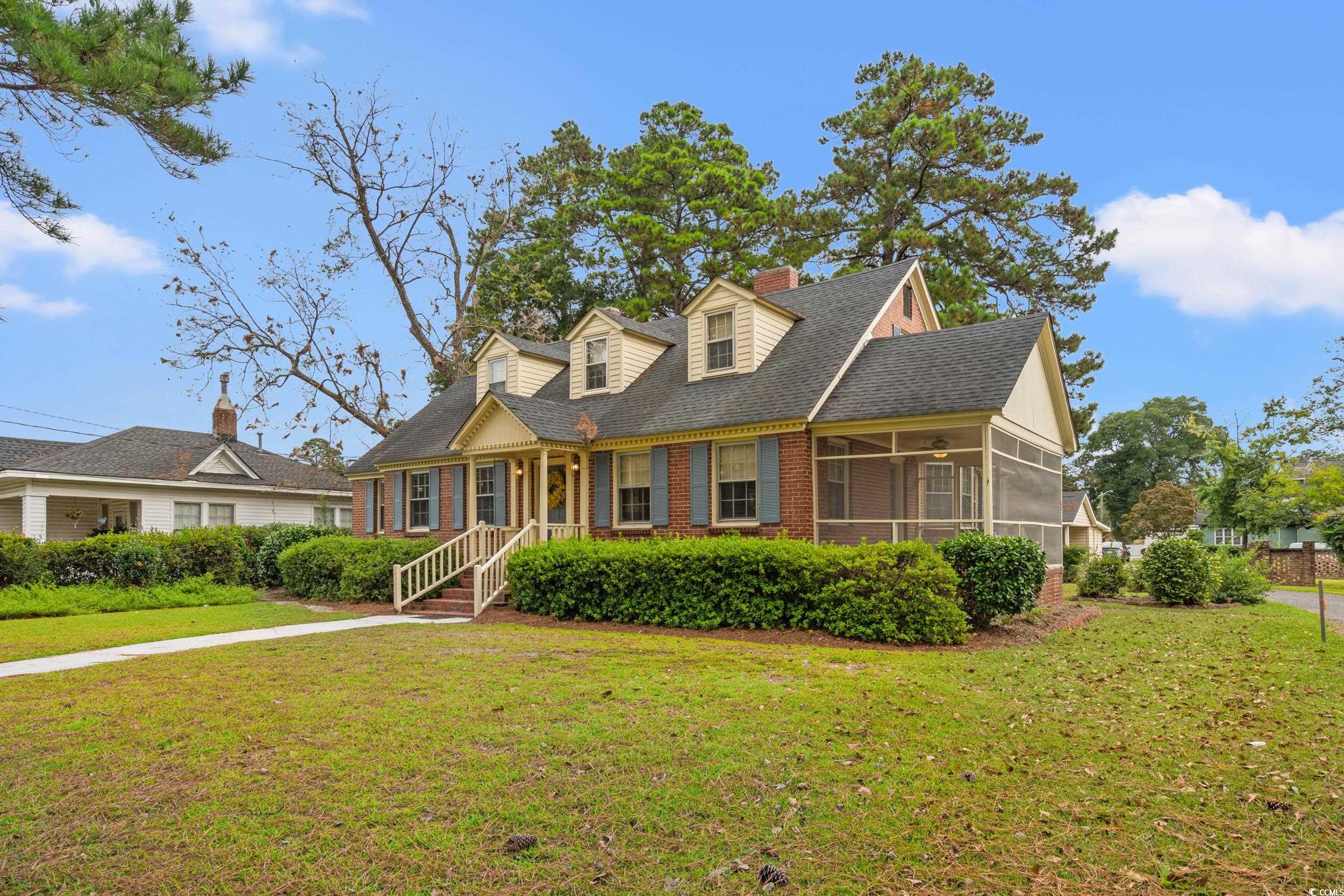 310 North Main Street Mullins, SC 29574 - Photo 12 of 35 Cape cod home with a front yard, roof with shingles, a sunroom, brick siding, and a porch