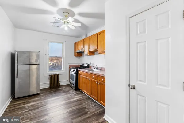 a kitchen with stainless steel appliances granite countertop a refrigerator a sink dishwasher a stove and white countertops with wooden floor