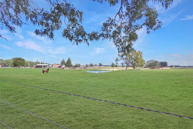 a view of a green field with trees in the background