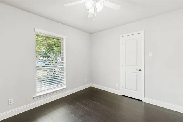 an empty room with wooden floor cabinet and windows