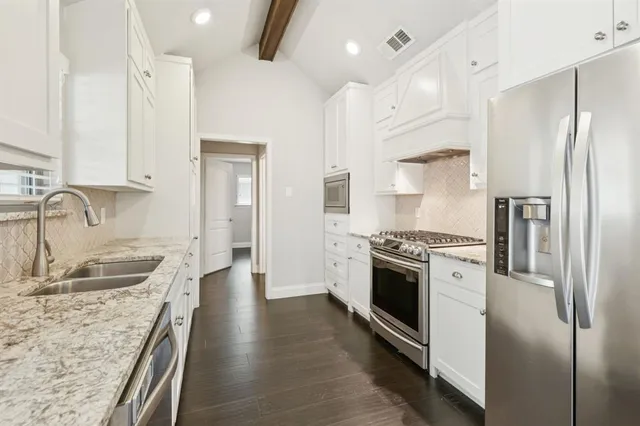 a kitchen with granite countertop a refrigerator stove and sink