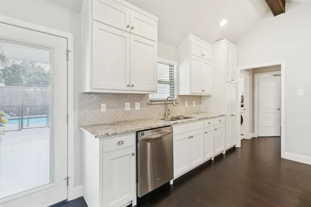 a kitchen with stainless steel appliances granite countertop a stove a sink and white cabinets
