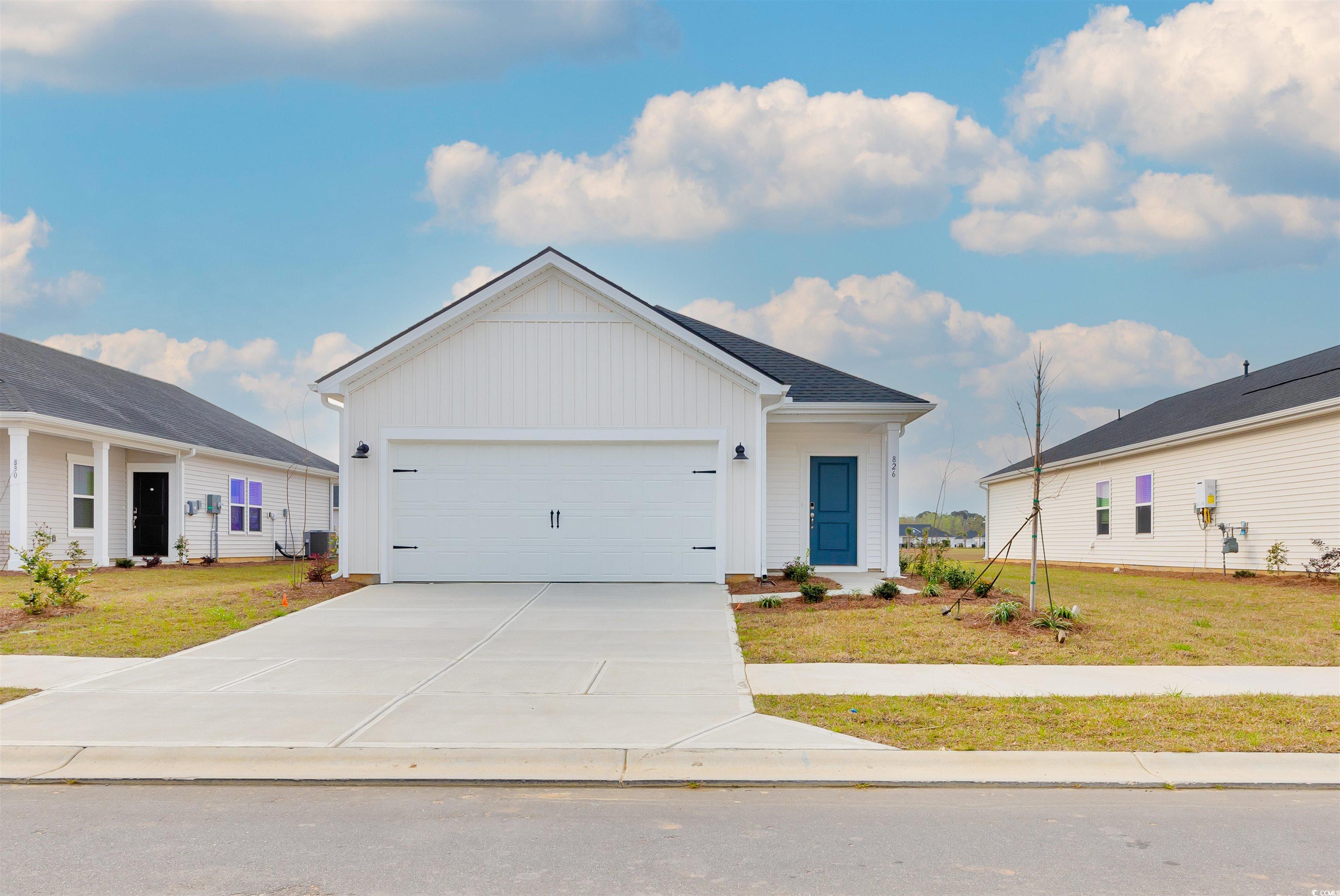 View of front of property with an attached garage, concrete driveway, a front yard, and board and batten siding