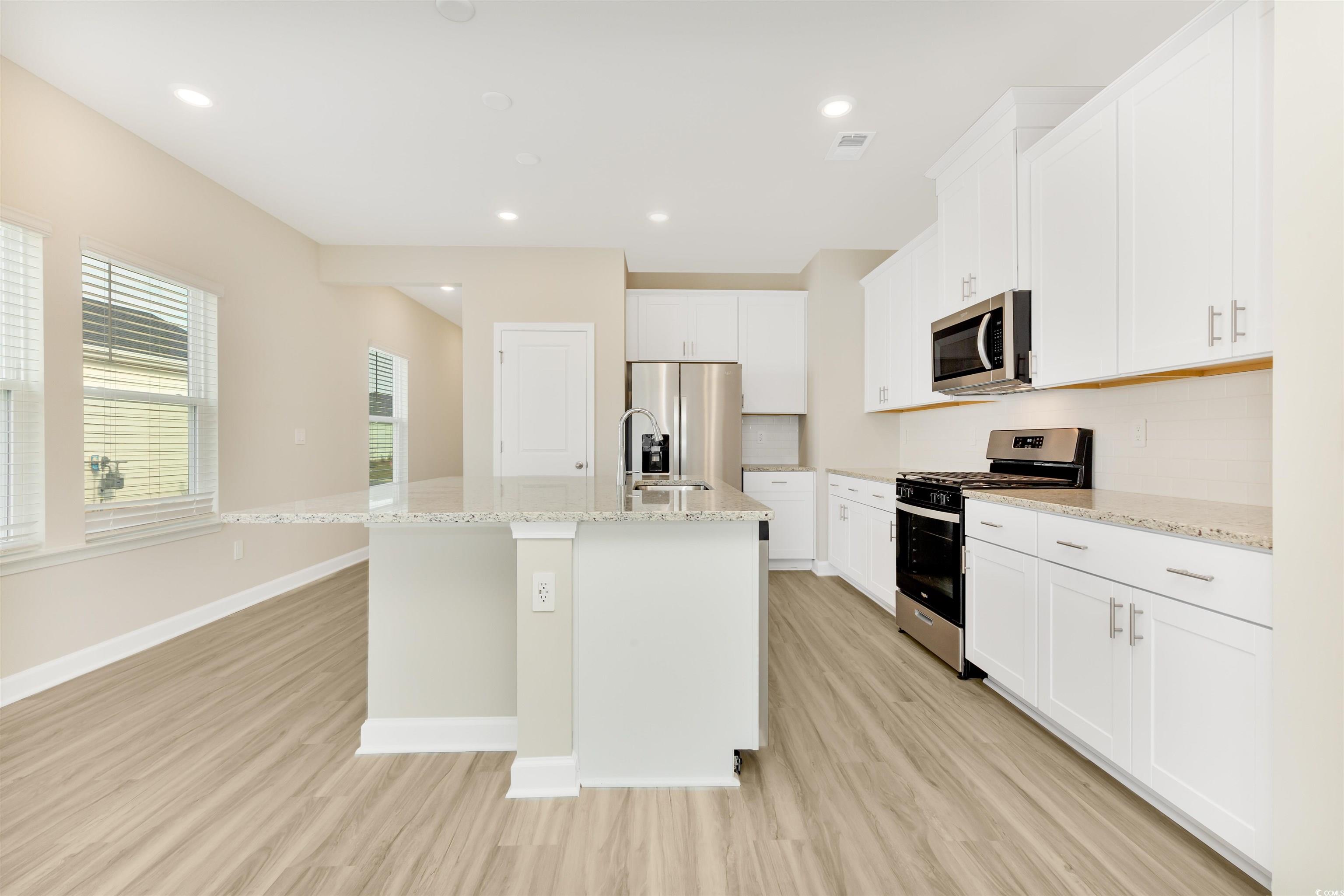 826 Cypress Preserve Circle Longs, SC 29568 - Photo 5 of 27 Kitchen with a kitchen island with sink, baseboards, light wood-style flooring, and stainless steel appliances